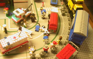 A scene of lego toys depicting a disaster. "Formal" actors like the police and an ambulance are present to help victims as well as "informal" actors- i.e citizens, both of which are employing coping actions in the situation.